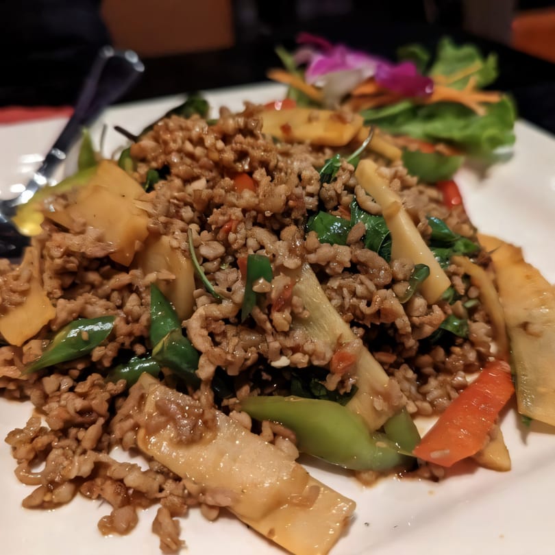 A close-up of Thai Basil Chicken (Pad Krapow Gai) with minced chicken, bamboo shoots, and basil.